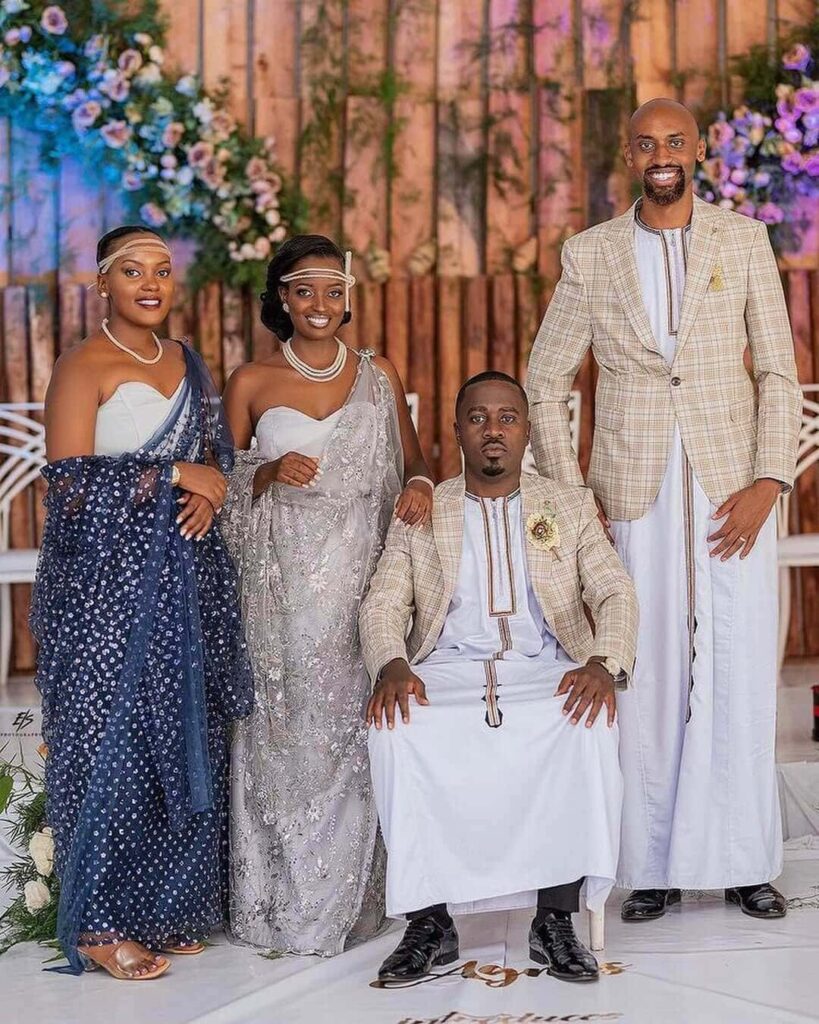 A groom and his groomsman in Kanzu pictured together with a bride and her bridesmaid in their gomesi outfits. Image Source: Instagram/@kanzu4you