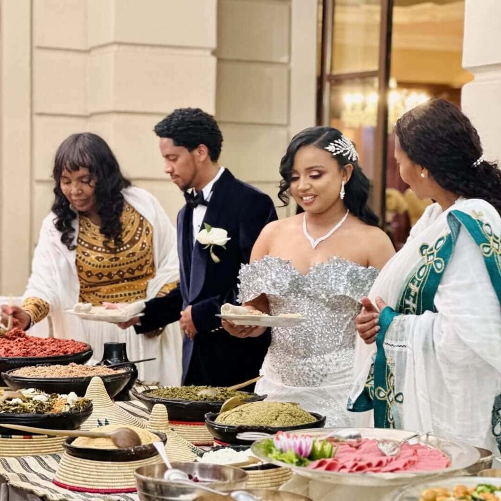 An Ethiopian couple being served delicious Gurage traditional food at their wedding. Image Source: Instagram/@abet_kitfo_catering